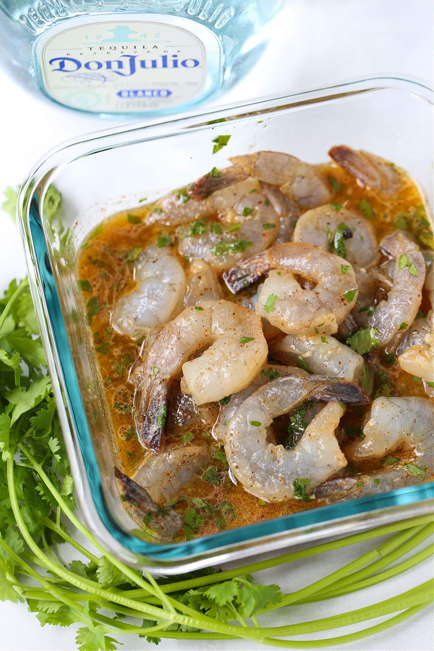 shrimp marinating in a dish with tequila bottle