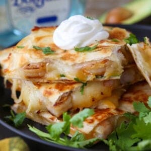 Tequila Shrimp Quesadillas stacked on a plate with tequila bottle