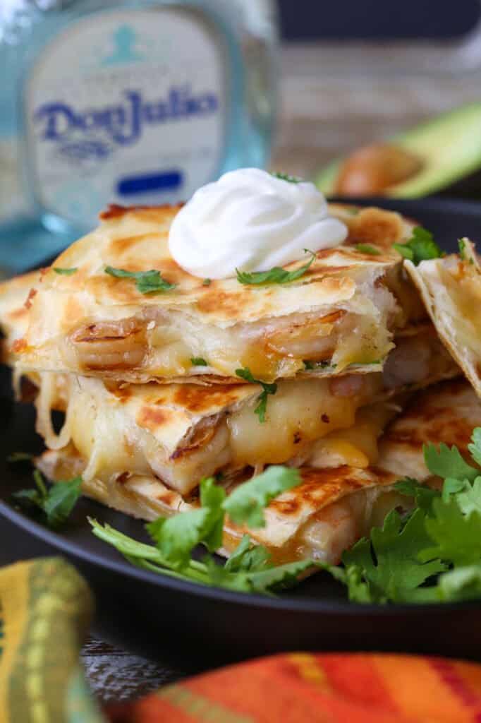 Tequila Shrimp Quesadillas stacked on a plate with tequila bottle
