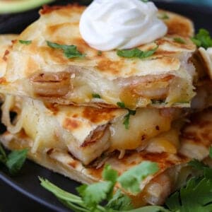 Tequila Shrimp Quesadillas stacked on a plate with sour cream
