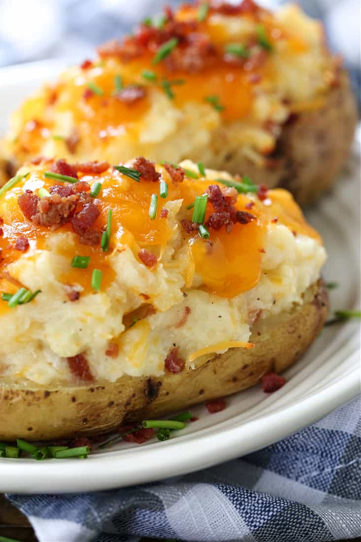 Twice Baked Potatoes are a delicious side dish that can be totally made ahead of time! Creamy, cheesy potato filling in a crispy baked skin! twice baked potato on a plate from the side