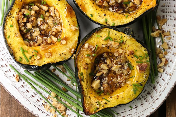 With a buttery texture and a golden caramelized crust, Acorn Squash with Brown Sugar and Walnuts features a sweet and nutty filling. Roasted acorn squash with walnuts and brown sugar on a platter.