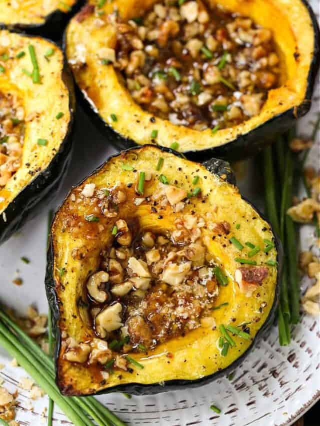 Two halves of an acorn squash hollowed out and filled with nuts.
