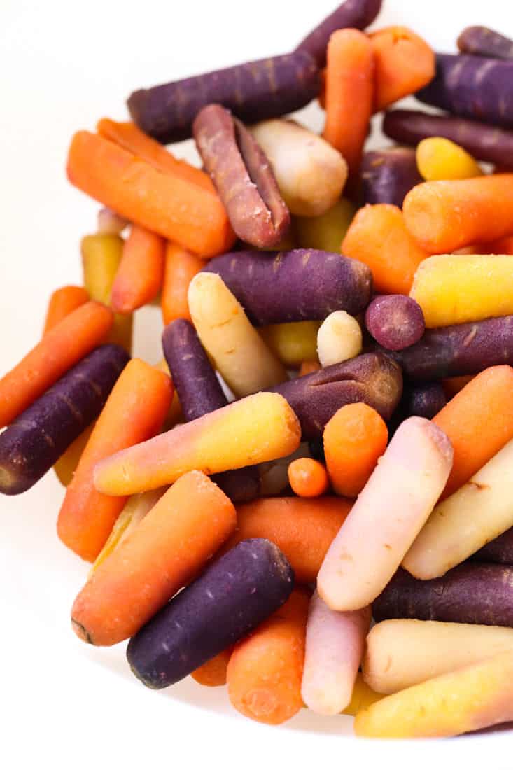 Colorful baby carrots in a white bowl