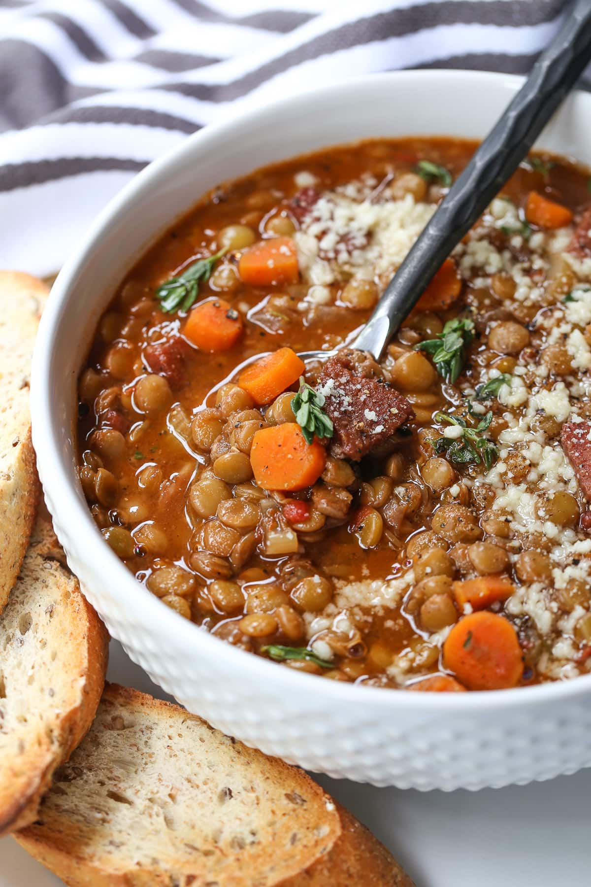 lentil soup with ham in white bowl with spoon