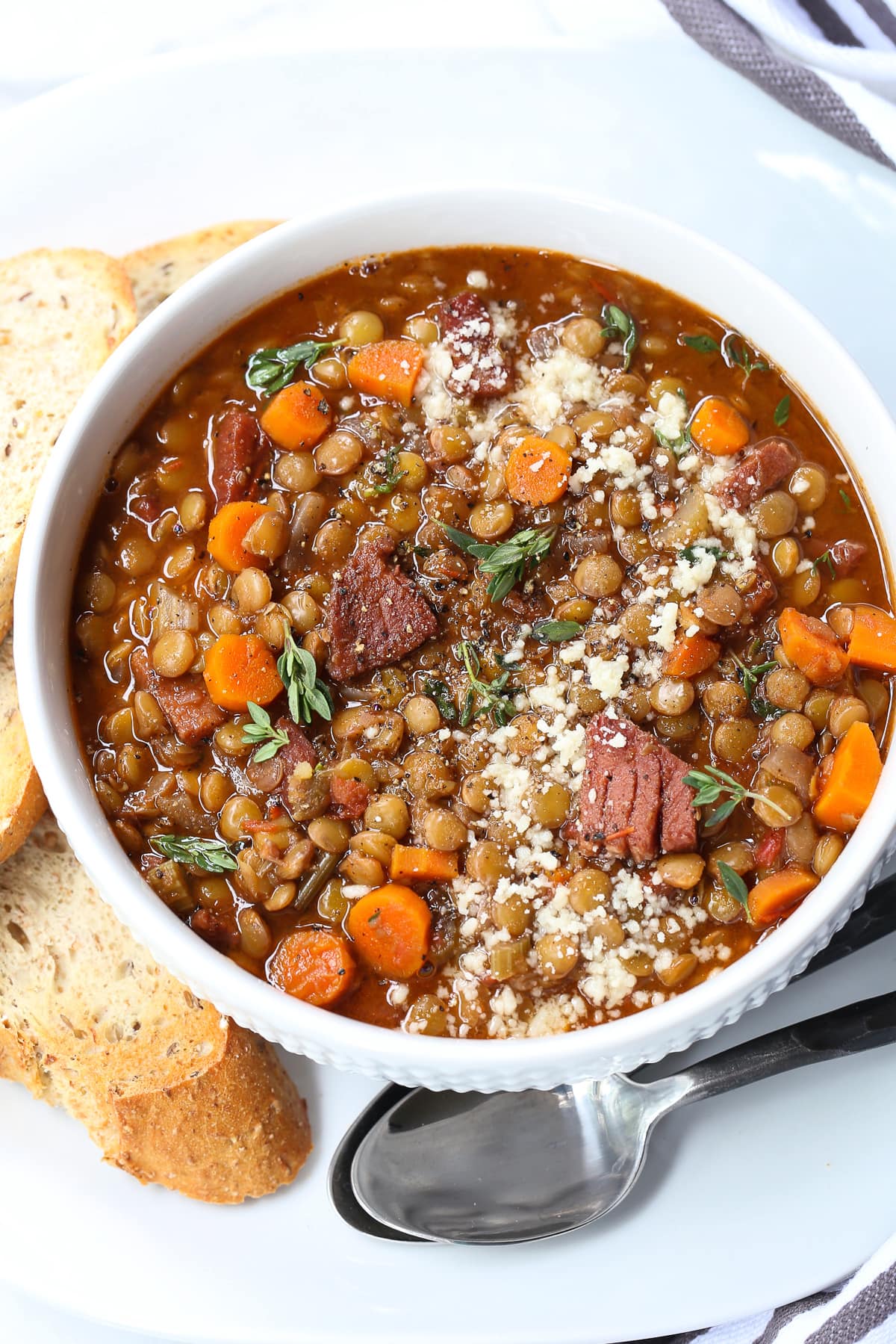 lentil soup with ham in a bowl with toast and spoon on the side