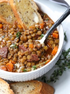 lentil soup recipe in white bowl with spoon and toast dipped in