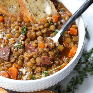 lentil soup recipe in white bowl with spoon and toast dipped in