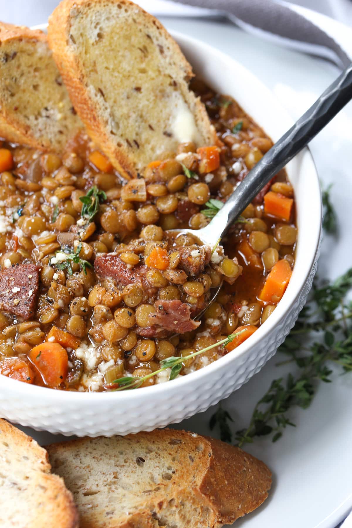 lentil soup recipe in white bowl with spoon and toast dipped in
