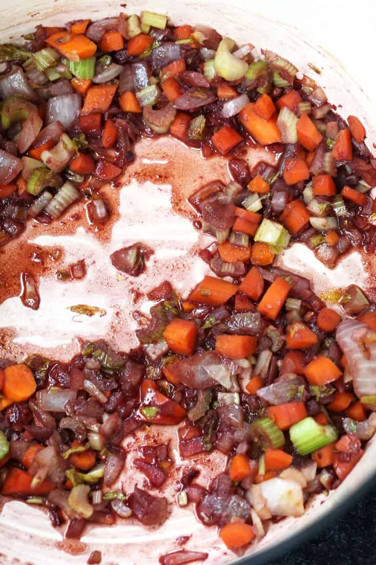 Red wine deglazing a pot with carrots, onions and celery