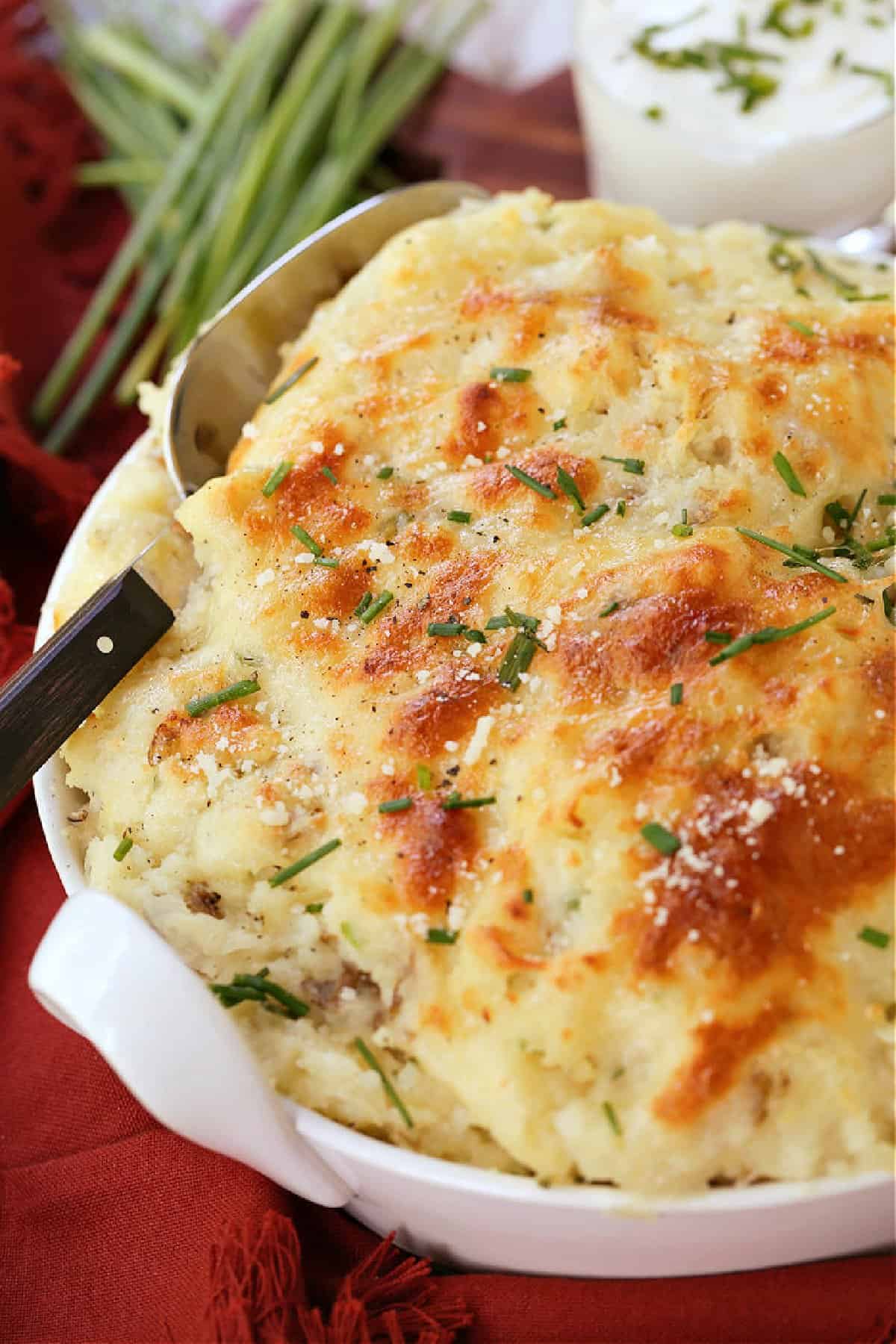 Potatoes Romanoff is a light and fluffy potato casserole with a unique cooking method! A make ahead side dish for parties and holidays! potato casserole in dish with serving spoon