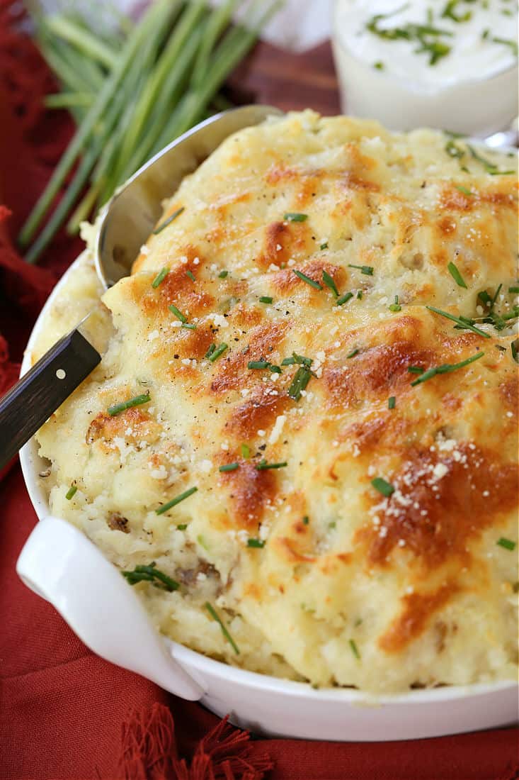 Potatoes Romanoff in a baking dish with serving spoon