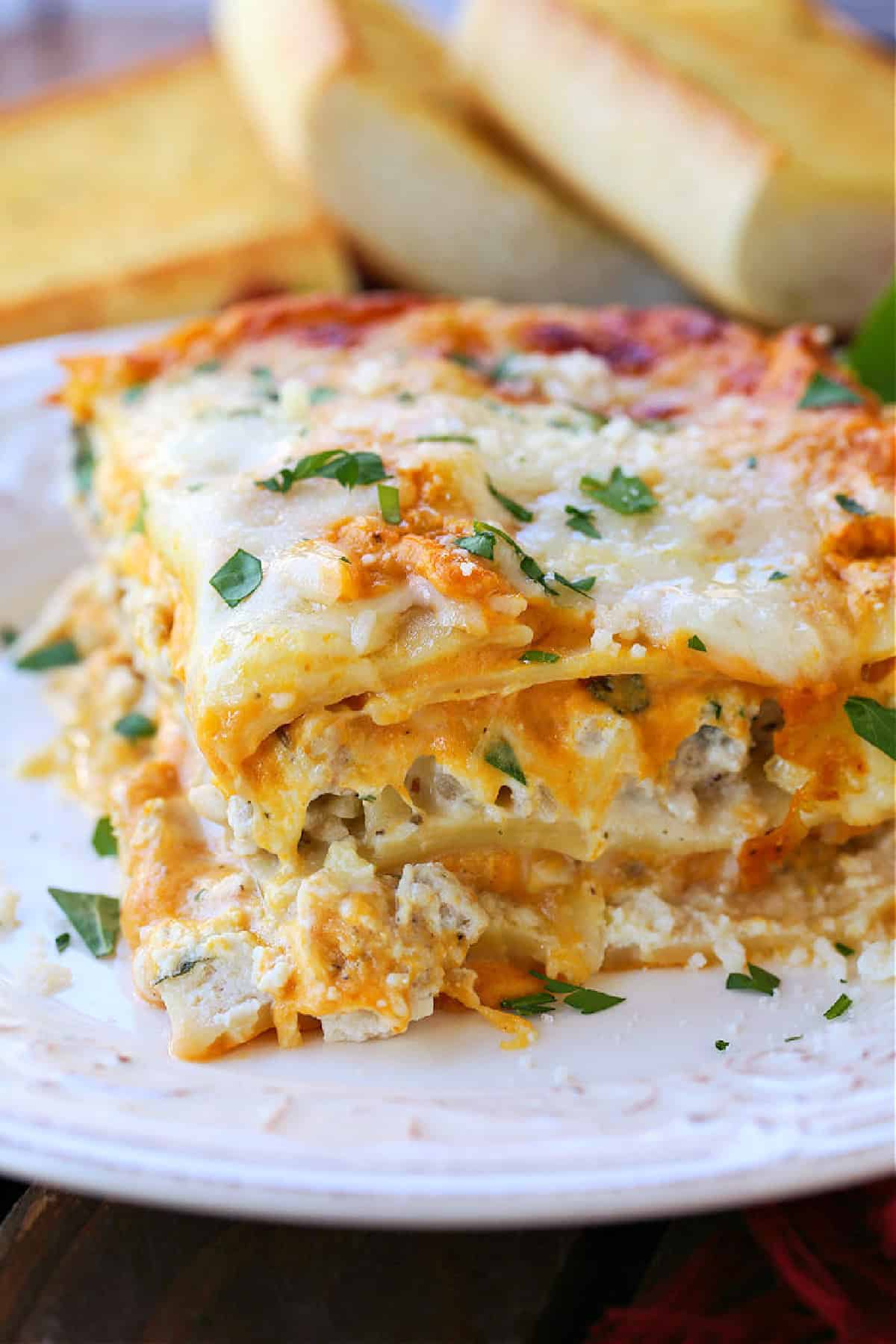 This Pumpkin Lasagna has the most delicious, creamy pumpkin Alfredo! All the cozy, fall vibes you're looking for in a lasagna recipe! slice of pumpkin lasagna on a white plate