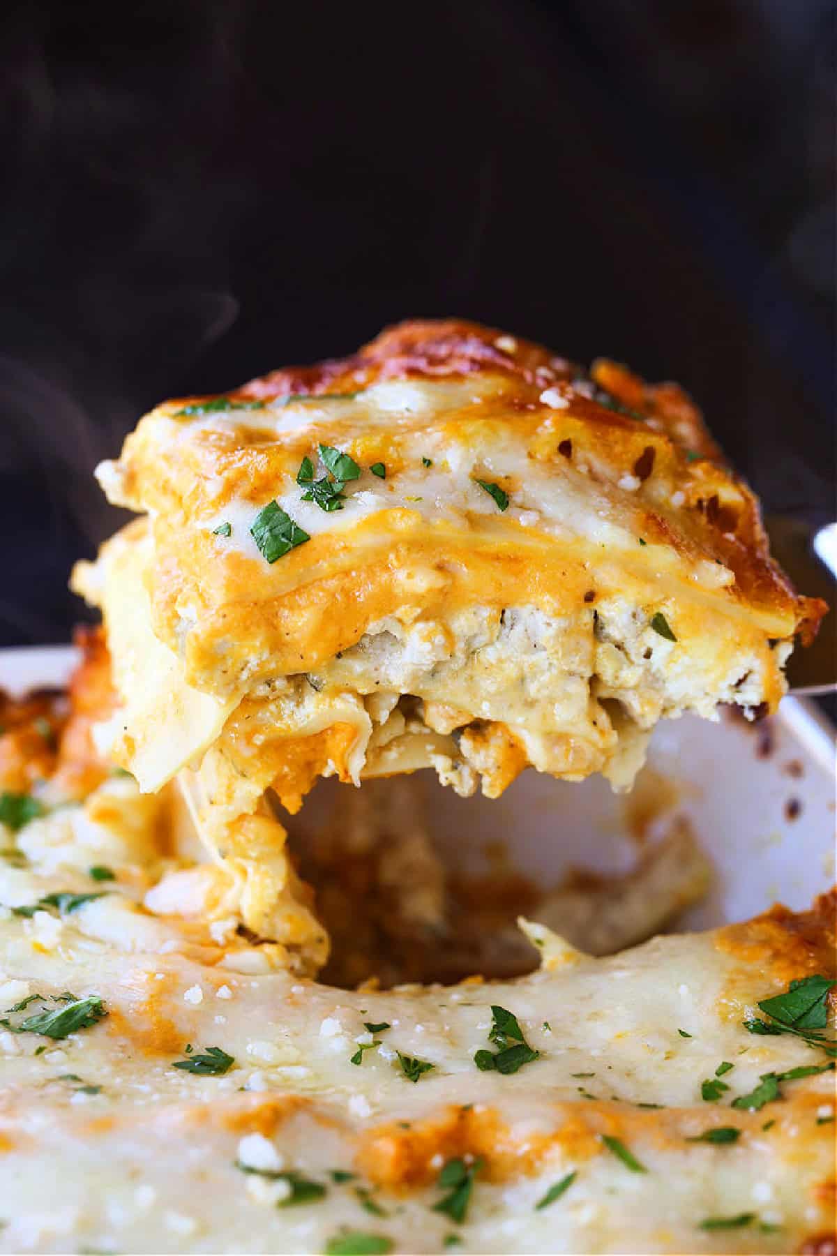 This Pumpkin Lasagna has the most delicious, creamy pumpkin Alfredo! All the cozy, fall vibes you're looking for in a lasagna recipe! pumpkin lasagna lifting out of baking dish
