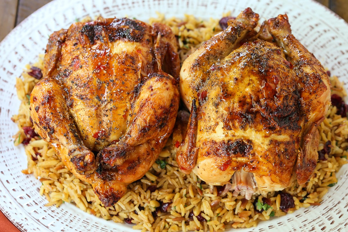 two cornish hens on a platter with rice pilaf