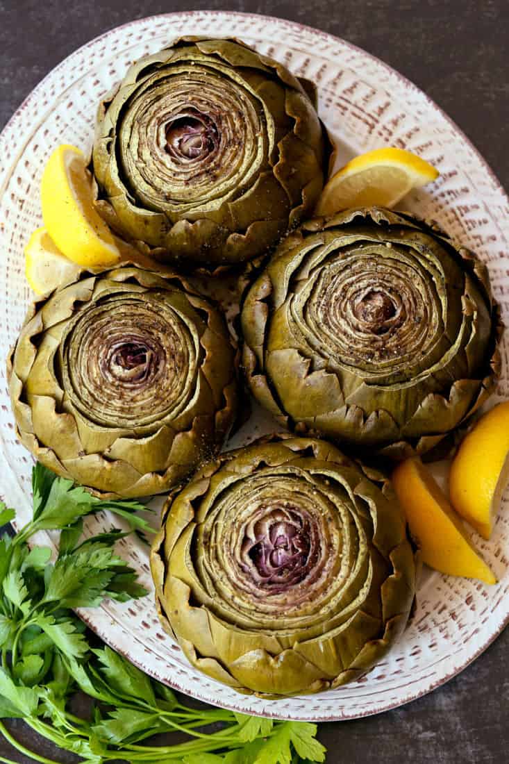 Steamed Artichokes with Garlic Aioli are so easy to make and so good for you! A gorgeous vegetable side dish or appetizer for everyday meals or holiday dinners! Steamed Artichokes with lemon wedges on a platter