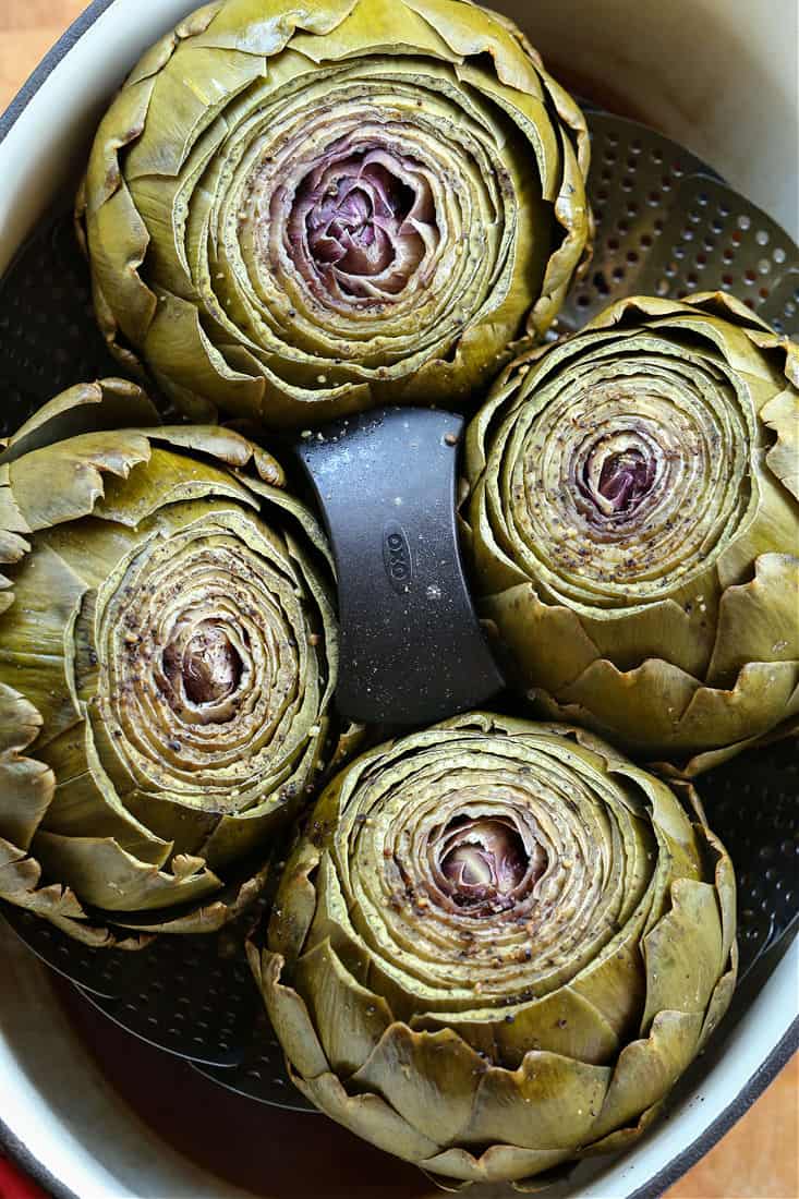 Steamed Artichokes with Garlic Aioli are so easy to make and so good for you! A gorgeous vegetable side dish or appetizer for everyday meals or holiday dinners! artichokes in a steamer basket