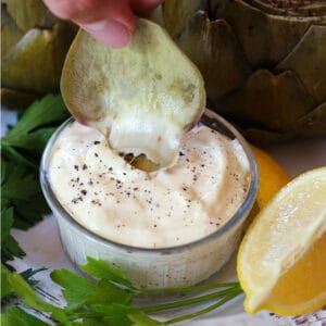 Steamed artichoke leaf dipping into garlic aioli