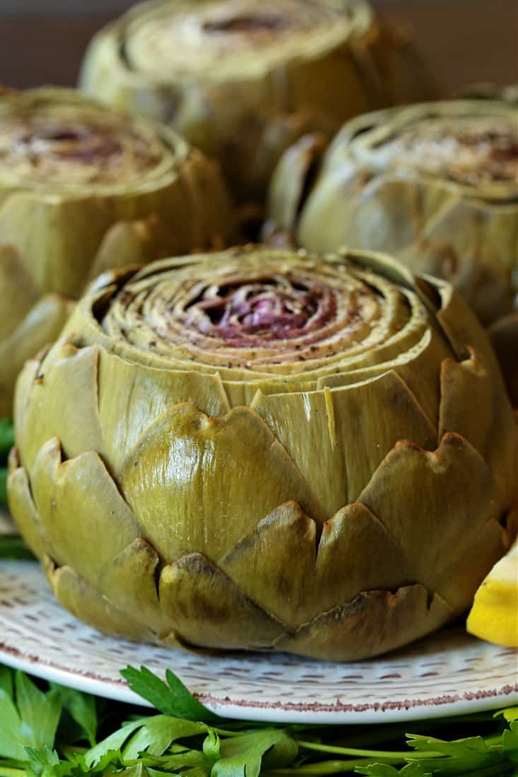 Steamed Artichokes with Garlic Aioli are so easy to make and so good for you! A gorgeous vegetable side dish or appetizer for everyday meals or holiday dinners! Steamed artichoke on a platter