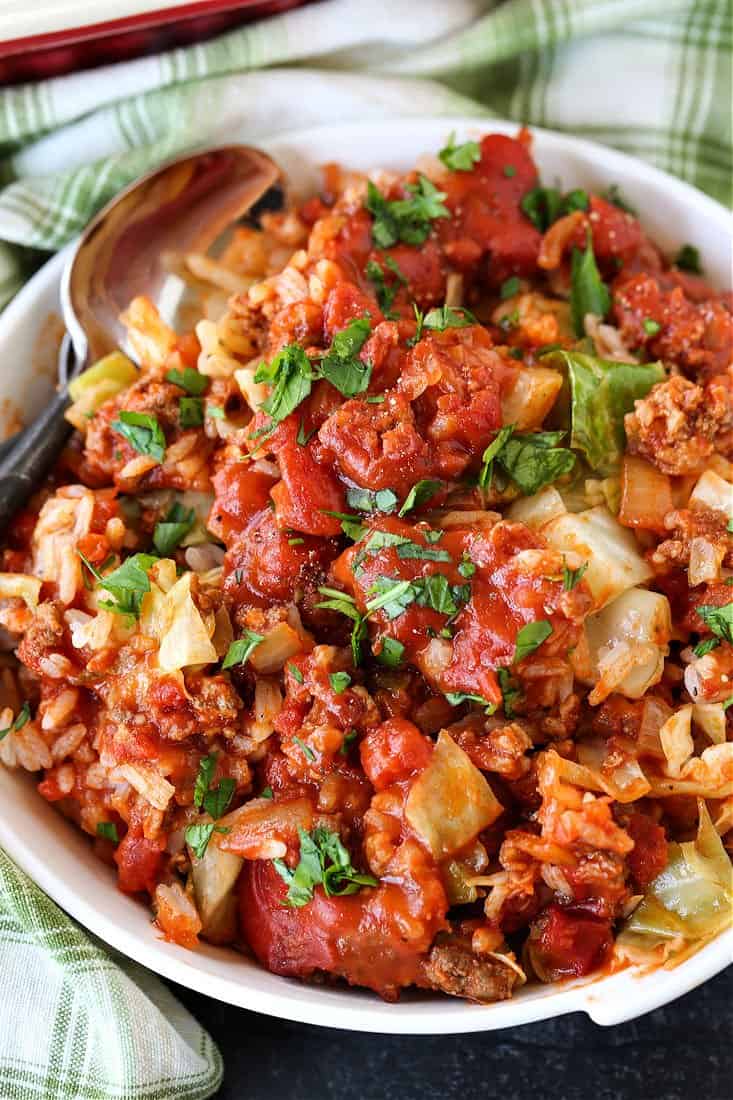 This Cabbage Roll Casserole is a comforting, easy to make dinner recipe! All your favorite cabbage roll ingredients in a delicious, easy casserole! Cabbage Roll Casserole in a bowl with spoon for serving
