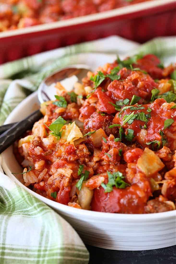 This Cabbage Roll Casserole is a comforting, easy to make dinner recipe! All your favorite cabbage roll ingredients in a delicious, easy casserole! Bowl with cabbage roll casserole and green napkin