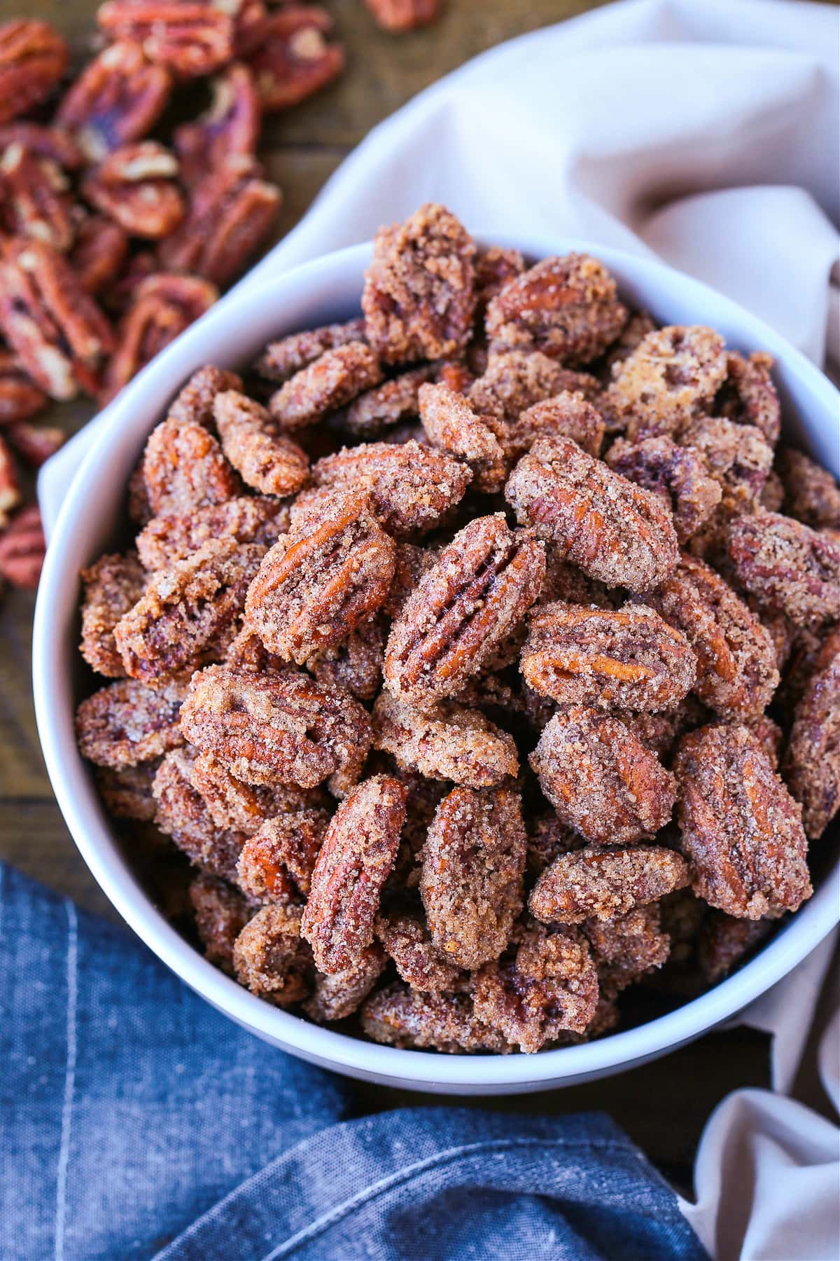 Our Candied Pecans Recipe is so addicting, you won't be able to stop eating them! A tasty snack recipe for parties, holidays and game days! candied pecans in a white bowl with napkin
