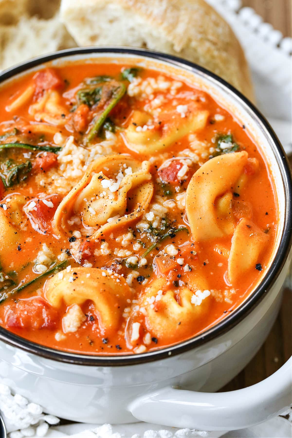 tomato soup with tortellini and parmesan cheese in white bowl