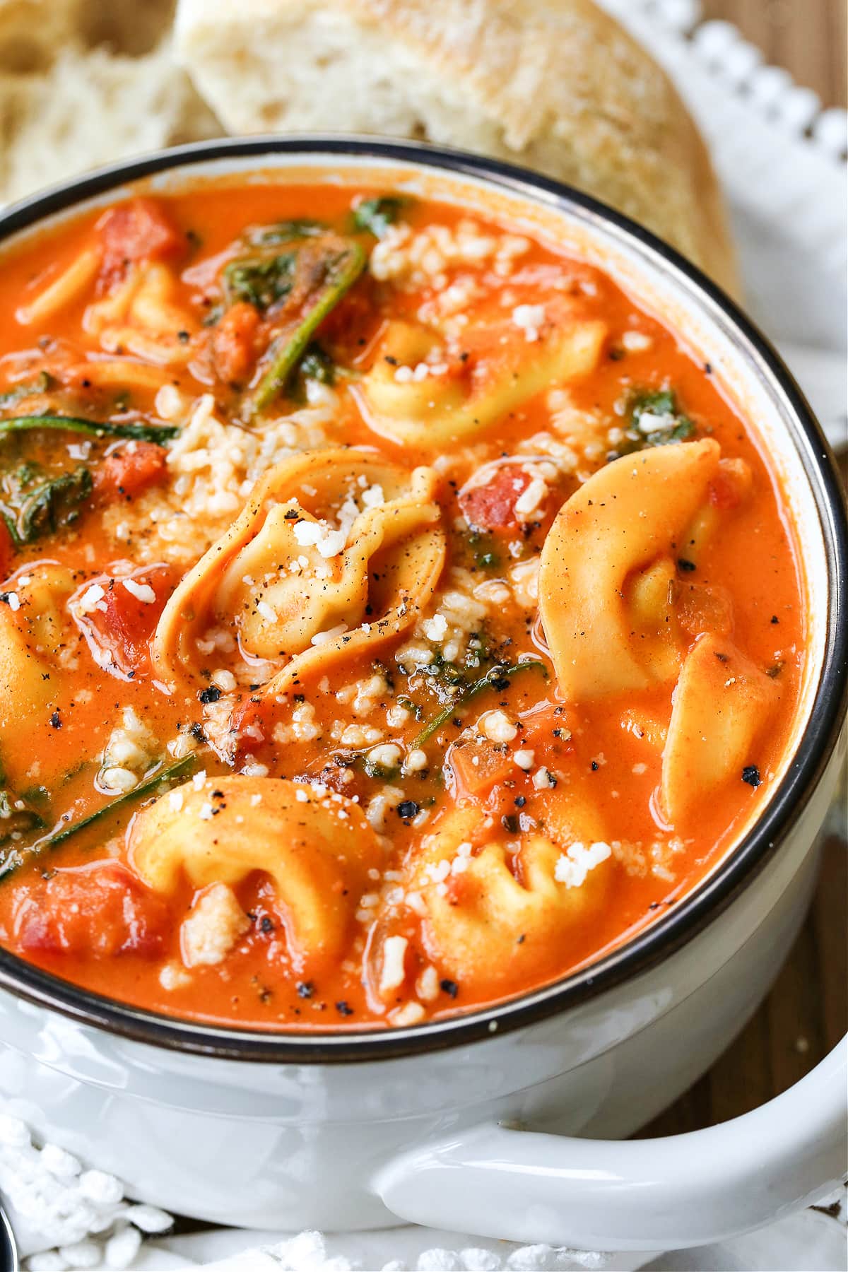 Our Creamy Tomato Tortellini Soup is one of our favorite soup recipes. So hearty and comforting and it's ready in just 30 minutes! tomato soup with tortellini and parmesan cheese in white bowl