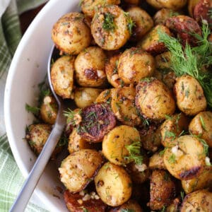 Garlic Dill Roasted Potatoes in a white bowl with spoon