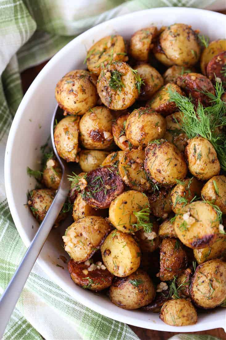 Garlic Dill Roasted Potatoes in a white bowl with spoon