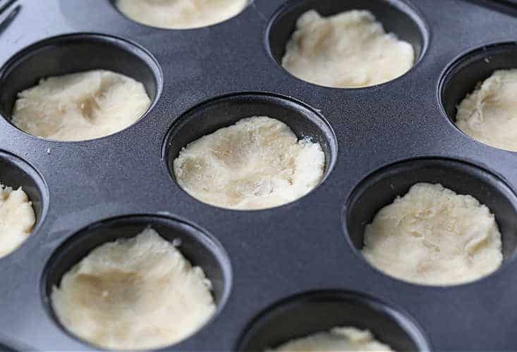 dough pressed into muffin tins for a cookie recipe