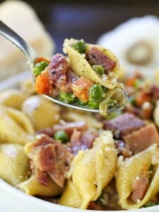 Pasta recipe with ham and peas on a spoon