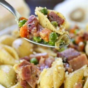 Pasta recipe with ham and peas on a spoon