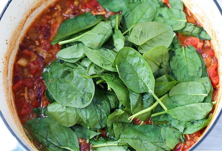 Spinach added to soup recipe in a pot