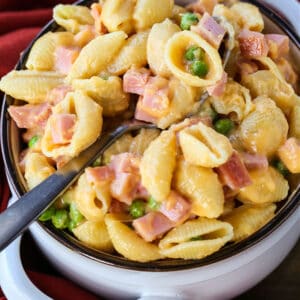 Pasta with cheese sauce and diced ham in a bowl with a spoon