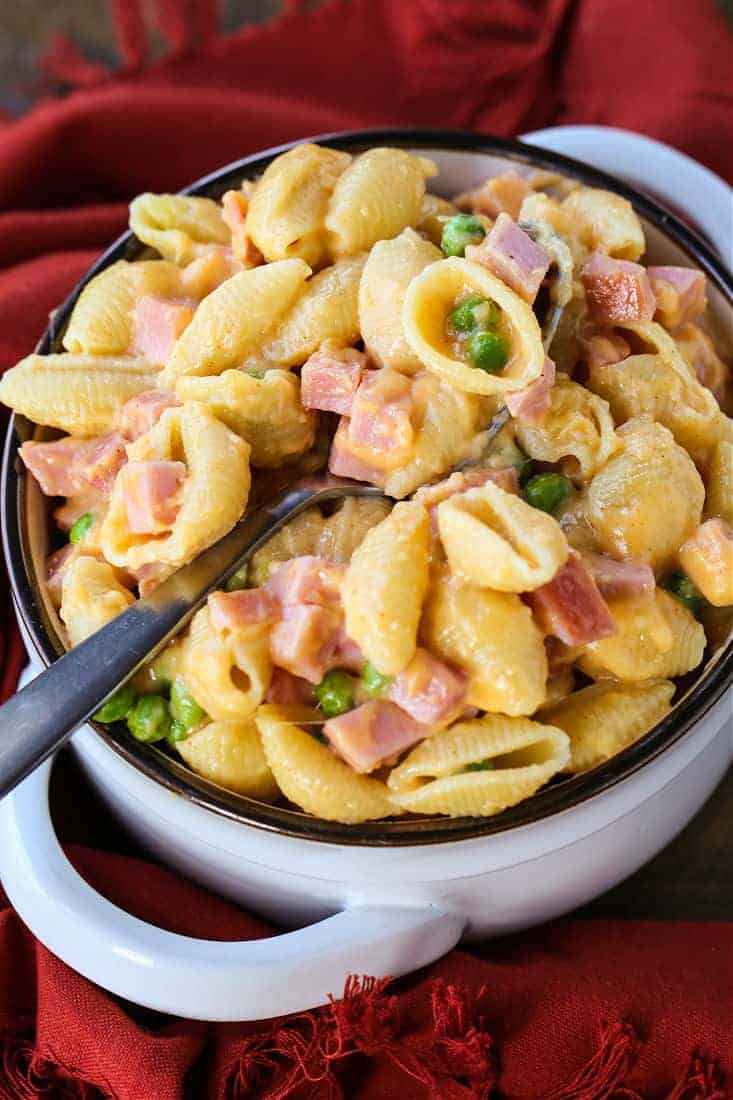 Pasta with cheese sauce and diced ham in a bowl with a spoon