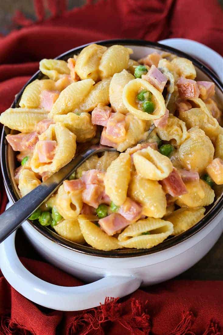 Pasta with cheese sauce and diced ham in a bowl with a spoon