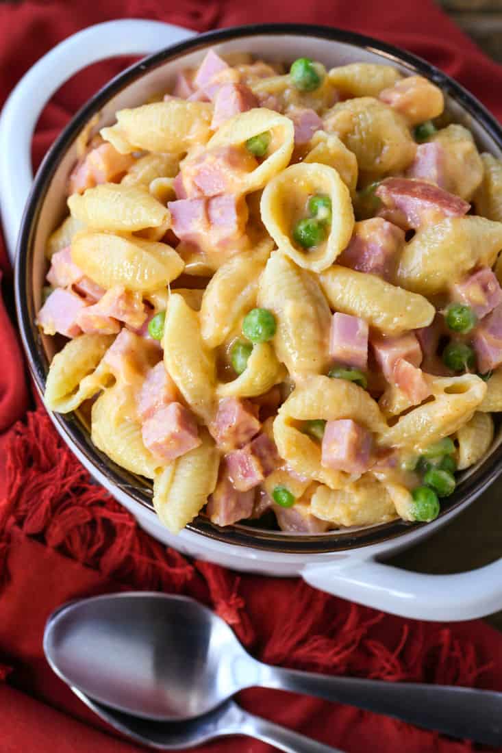 Cheesy shells and ham in a bowl with spoons