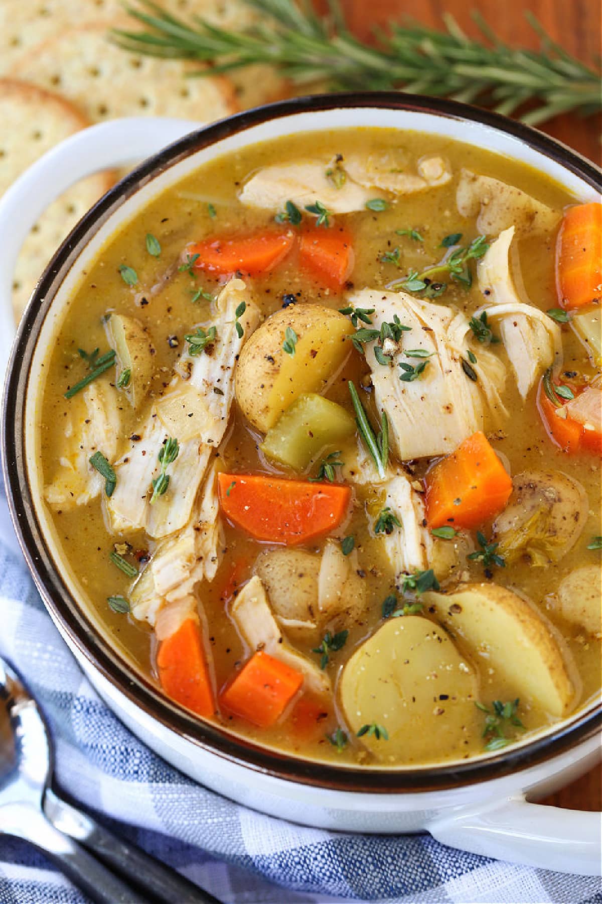 Comforting Chicken Stew is always a dinner favorite. Tender, poached chicken with fresh herbs and hearty vegetables in a light, creamy broth! chicken stew in white bowl with spoon