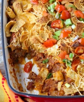 Frito Pie in a baking dish with a scoop taken out