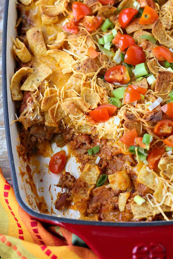 Frito Pie in a baking dish with a scoop taken out