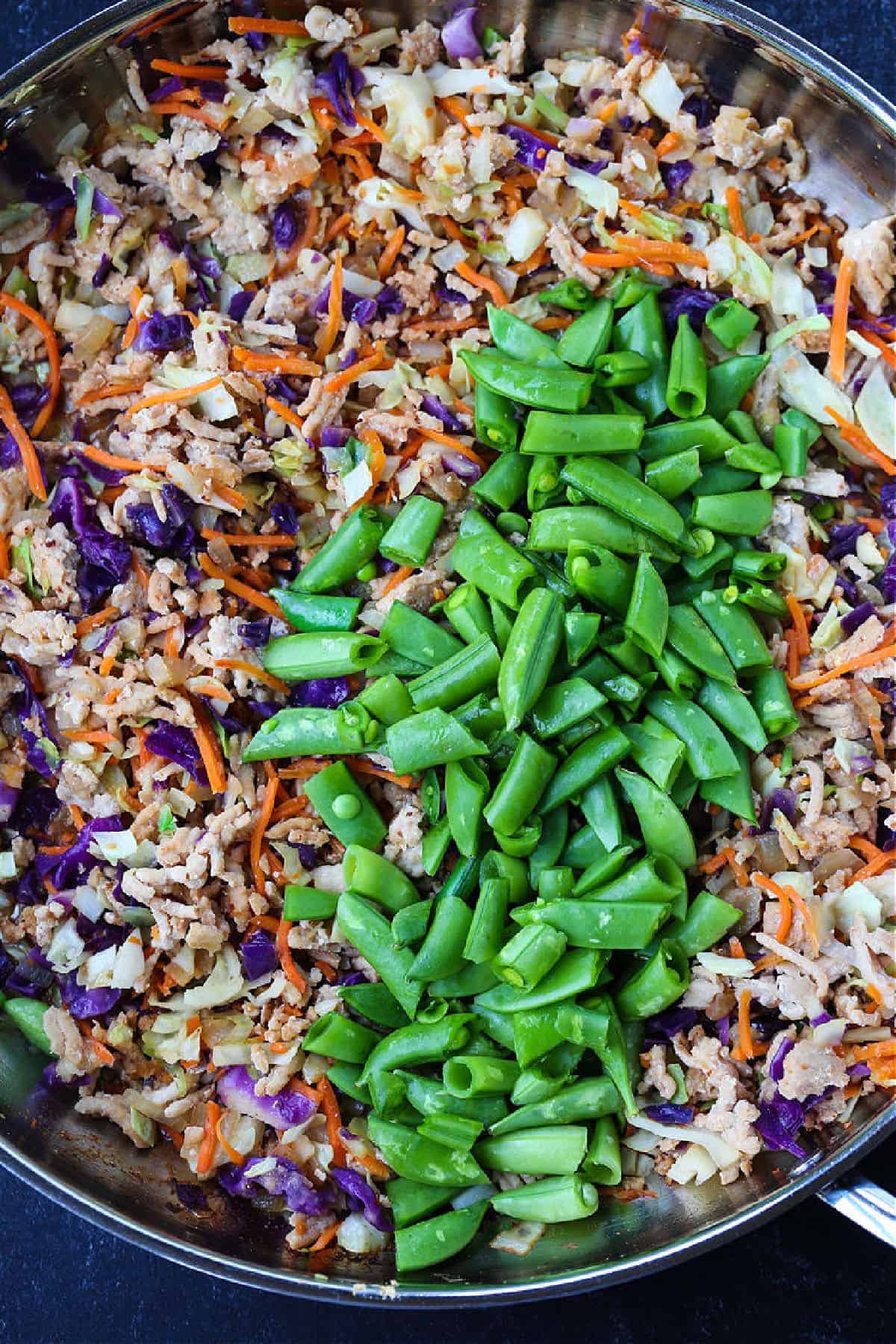 Peanut Chicken Fried Rice is packed with tons of vegetables and lean ground chicken tossed with the most addicting, creamy peanut sauce! ground chicken and cabbage in a skillet with chopped snow peas and a sriracha drizzle