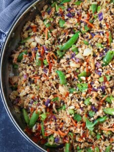 fried rice in a skillet with chopped snow peas and a sriracha drizzle