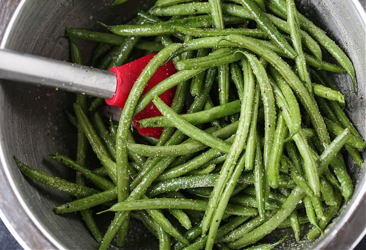 This Steak Sheet Pan Dinner is an easy and delicious way to enjoy a steak dinner at home! Everything cooks on one pan so clean up is a breeze! Green beans in a bowl with seasonings