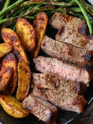 Sliced steak, potatoes and green beans on a plate