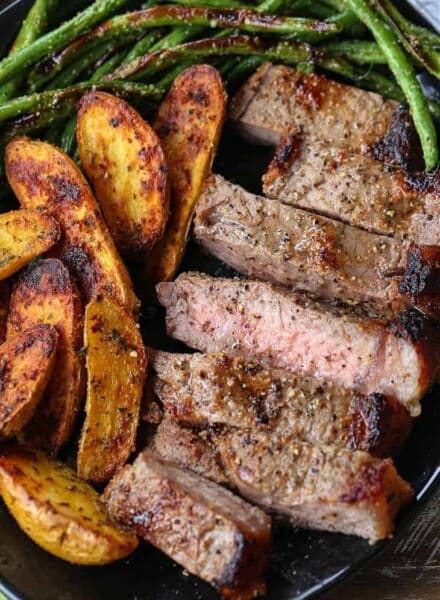 Sliced steak, potatoes and green beans on a plate