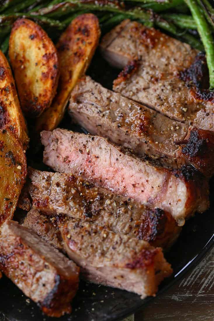 This Steak Sheet Pan Dinner is an easy and delicious way to enjoy a steak dinner at home! Everything cooks on one pan so clean up is a breeze! Sliced strip steak with potatoes and green beans