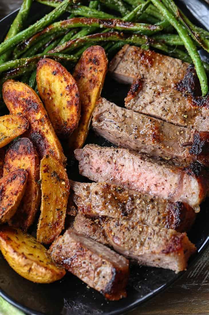 Sliced steak, potatoes and green beans on a plate