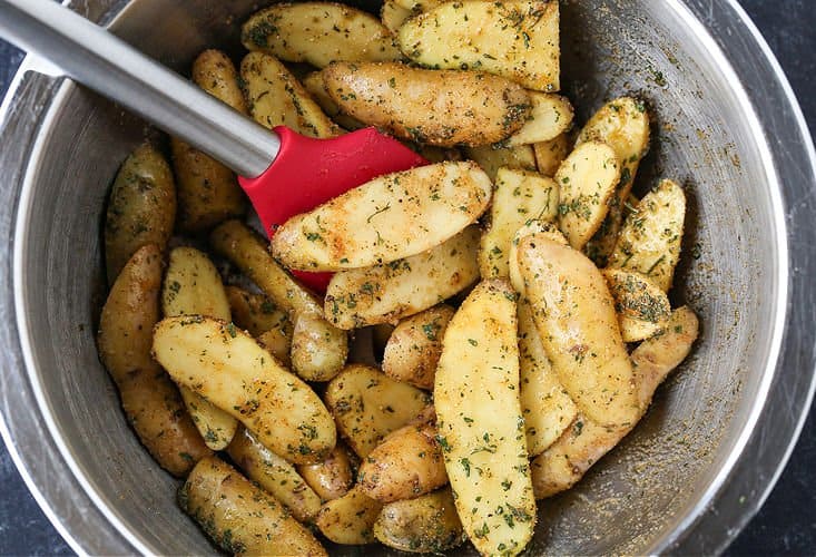 This Steak Sheet Pan Dinner is an easy and delicious way to enjoy a steak dinner at home! Everything cooks on one pan so clean up is a breeze! Fingerling potatoes with seasonings in a bowl