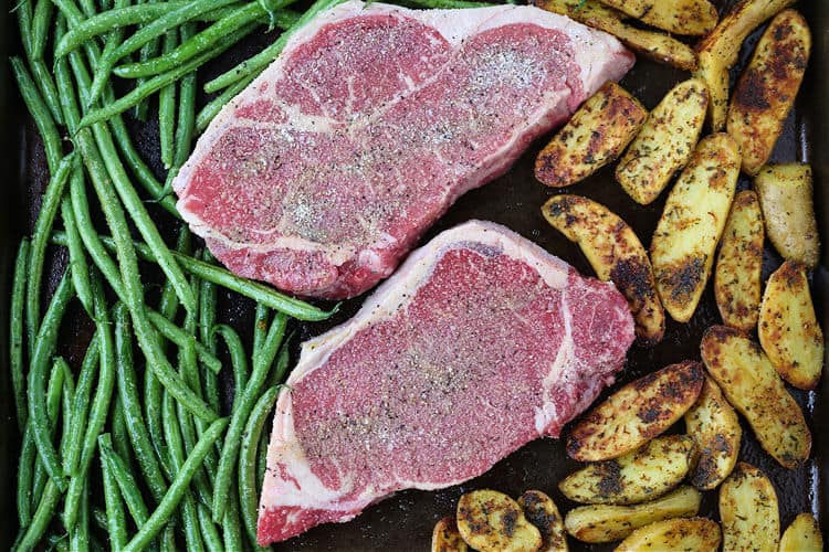 strip steaks on a shwet pan with green beans and potatoes